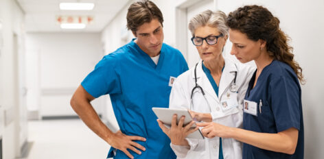 Shot of a group of medical practitioners using a digital tablet together in a hospital hallway